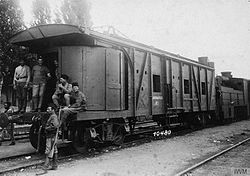 Approximately 4 soldiers, some of whom are armed, posing in front of a heavily armoured train car.