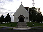 A square with small pine trees with a staircase leading to a chapel