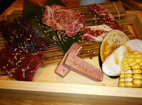 在木制小船和竹简上摆盘的几种日式烧肉的肉类