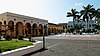 Panorama d'une place du centre historique de Tlacotalpan. Des bâtiments à arcades occupent le fond de la place. Des palmiers s'élèvent en son centre.