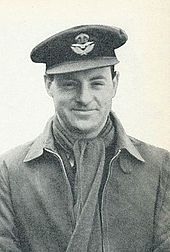 Photo en plan américain de Whitney Straight, portant l'uniforme de la Royal Air Force, une écharpe et une casquette.