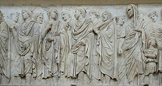 Three flamines in their distinctive pointed headgear, grouped to the centre of a panel from the Ara Pacis Ara pacis fregio lato ovest 2 A.JPG