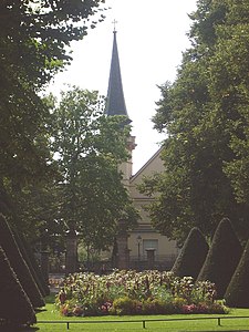 Vue de l'église Saint-Louis, avec parterre de fleurs, près de la porte-ouest du Jardin français.