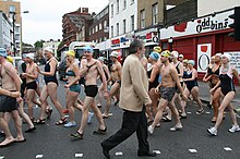picture shows a group of people wearing swim wear walking along a London Street