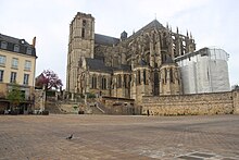 Vue d'une place avec une cathédrale, une muraille, une fontaine et des édifices contemporains.