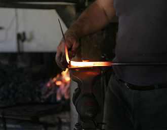 Blacksmiths judge workpiece temperatures by the colour of the glow. Blacksmith at work.jpg
