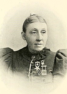 An older white woman, with medals pinned to her jacket.