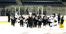 Photo de joueurs entourant un entraîneur qui leur parle.