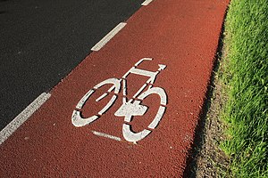 English: A red bike lane on the side of a high...