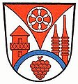 Landkreis Obernburg a.Main (–1972) In Silber über einer gesenkten, gebogenen blauen Leiste, darunter eine rote Weintraube, eine gestürzte, eingebogene rote Spitze, darin ein sechsspeichiges silbernes Rad; vorne ein roter römischer Wachtturm, hinten nebeneinander zwei rote Kesseltürme.