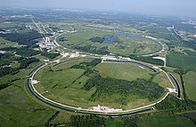 Aerial photo of the Tevatron (background ring) and Main Injector (foreground ring which is not actually circular) rings at Fermilab. The Tevatron ring also contains Main Ring and a section of it is still used for downstream experiments. The Main Injector below (about half the diameter of the Tevatron) is for preliminary acceleration, beam cooling and storage, etc. Fermilab.jpg