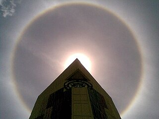Vòng hào quang 22° quanh Mặt Trời, phía trên tòa nhà PT Semen Padang tại Padang, Indonesia, ngày 2 tháng 10 năm 2009, lúc 11:09 sáng