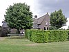 Boerderij met woongedeelte dat dwars voor de stal is gebouwd en een rieten zadeldak tussen puntgevels met vlechtingen draagt. Vensters met luiken en zesruitsschuiframen. De stal heeft een met riet en pannen gedekt wolfdak