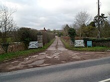 photo d'un portail blanc et d'un chemin menant à une bâtisse.