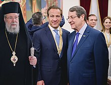 From left to right: Archbishop Chrysostomos II, Roys Poyiadjis, and President Nicos Anastasiades at a ceremony to celebrate the repatriation of a mosaic stolen from the church of Panagia Kanakaria. Poyiadjis wears the Golden Medallion of St. Paul, awarded to him for his contribution in the repatriation. RoysPoyiadjisMedal.jpg