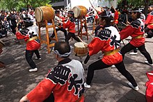 Penampil dari grup Soh Daiko tampil di luar ruangan dengan berbagai drum di depan hadirin.