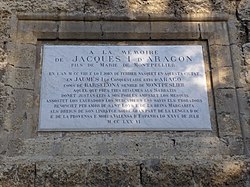 «En memòria de Jaume I d'Aragó, fill de Maria de Montpeller: en l'any 1208 i el dia 2 de febrer nasqué en esta ciutat en Jaume I el Conqueridor, rei d'Aragó, comte de Barcelona i senyor de Montpeller, el qual prengué tres reialmes als sarraïns, donà lleis justes als seus pobles, emparà els mesquins, sostingué els llauradors, els mercaders, els savis i els trobadors, renuncià per mor de sant Lluís i de la reina Margarida als drets del seu llinatge sobre gran part del Llenguadoc i la Provença i morí a València d'Espanya el 26 de juliol de 1276.»