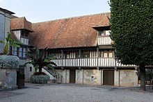 Color photograph of a half-timbered house at the end of a courtyard.