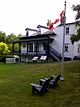 Два стула Muskoka и флаг Канады с видом на коттедж Хоторн.