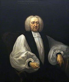 A middle-aged white man seated and wearing Georgian-era English clerical robes.