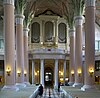 interior of the church, view to the organ, light pink columns, grey benches, organ case white and gold