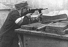 Home Army soldier armed with Blyskawica submachine gun defending a barricade in Powisle District of Warsaw during the Uprising, August 1944 Uprising defender.jpg