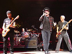 U2 performing at Madison Square Garden in November 2005, from left to right: The Edge; Larry Mullen Jr. (drumming); Bono; Adam Clayton