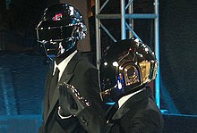 Two men wearing grey jumpsuits and robot helmets.