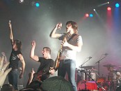 Underoath onstage, gesturing to the crowd