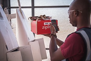 A Zipline flight operator scans a package barcode before inserting into the belly of a Zipline drone.