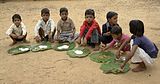 A8 Schoolchildren in Chambal, Madhya Pradesh eating a mid-day meal. The Mid-Day Meal Scheme attempts to lower rates of childhood malnutrition in India.