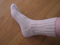 A hand knitted white lace sock made out of han...