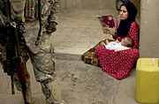 An Iraqi woman looks on as U.S. Soldiers search the courtyard of her house during a cordon and search in Ameriyah, Iraq.  House searches by U.S. soldiers are a common occurrence in the Iraq war.