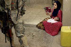 An Iraqi woman looks on as U.S. Army Soldiers ...