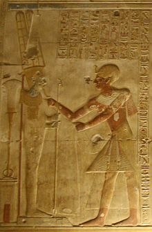 Relief, das einen prächtig gekleideten ägyptischen Mann zeigt, der sich einer männlichen Figur auf einem Sockel nähert