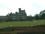 a castellated house viewed cross a field with sheep