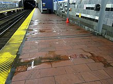 A station platform with several puddles of muddy water