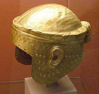 Meskalamdug helmet, British Museum electrotype copy, original was in the Iraq Museum, Bagdad. The holes around the border suggest that another piece was normally affixed, as for example in the full mask attributed to Sargon of Akkad. The hairbun attached at the back of the head is visible in other rulers as well, such as Sargon or Eannatum in the Stele of the Vultures. Golden helmet of Meskalamdug in the British Museum.jpg