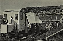 Marie Krogh procède à des mesures ou à des réglages sur un appareil relié à une cabine fermée installée dans la toundra du Groenland.