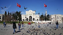 A triumphal arch adjacent to a Turkish flag and in front of an open plaza