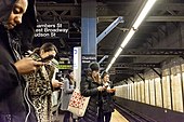 Passengers using smartphones at a subway station NYCS smartphones vc.jpg