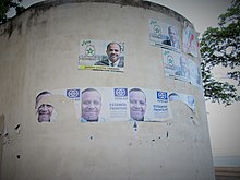 Mur à São Tomé, sur lequel sont collés plusieurs affiches électorales sur différentes hauteurs. Quelques-unes sont déchirées.