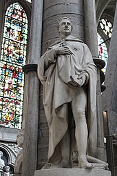 Die Statue Castlereaghs im nördlichen Querschiff der Westminster Abbey, die vor einer Säule steht, hinten links die Fenster der Westminster Abbey mit farbigen Motiven