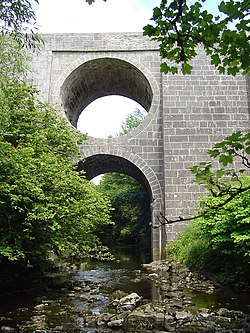 Stone bridge over a shallow river, in a wooded gorge. For design, see article text.