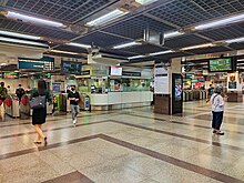 People walking at the station concourse level, with faregates that separate the paid and unpaid areas.