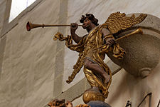 The "renommé" at the summit of the pulpit canopy plays a trumpet, her foot resting on a globe