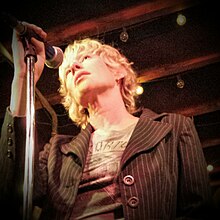 Timms at a microphone, photographed from below