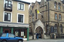 Le drapeau en berne à l’entrée d’un bâtiment néo-gothique, dans une rue de centre-ville.