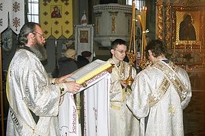 Subdeacons holding the episcopal candles while deacon reads the Gospel 4 Sanok, trikirion and dikirion, being held by subdeacons during the blessing of holy water.jpg