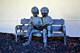 A statue of children reading to one another in front of the old School No. 57 building on Costar Street.